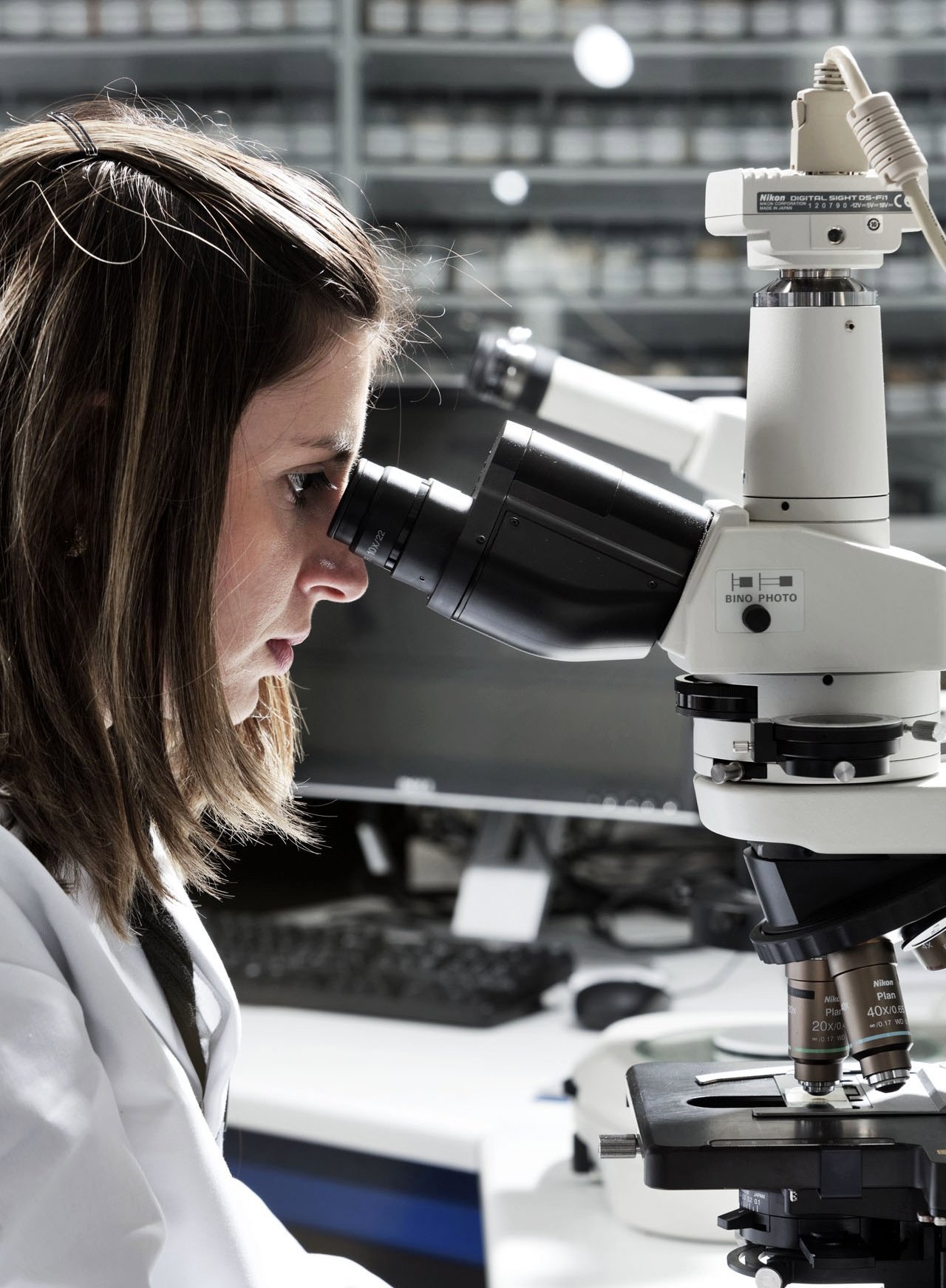 A lab scientist seeing microbes in feed over microscope 