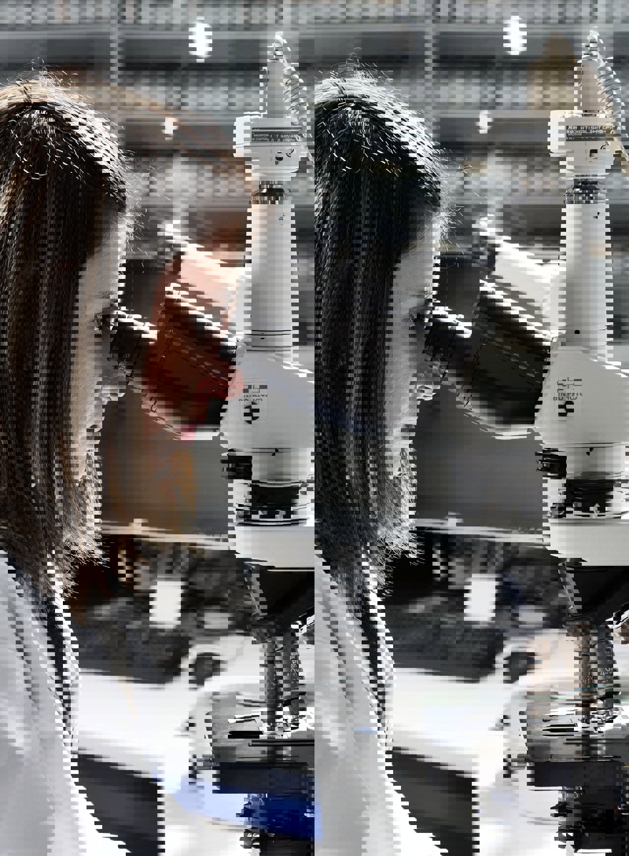A lab scientist seeing microbes in feed over microscope 